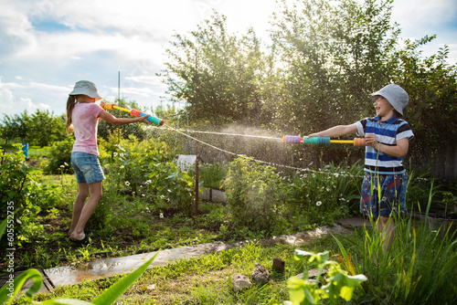 Canvas Print Two kids playing with water guns in backyard