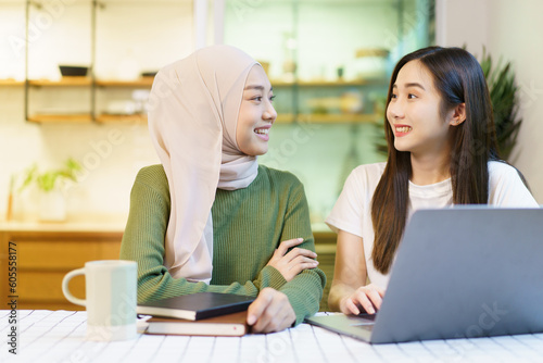 Happy cheerful Asian females university student discussing or doing a homework together in the pantry area in dormitory.