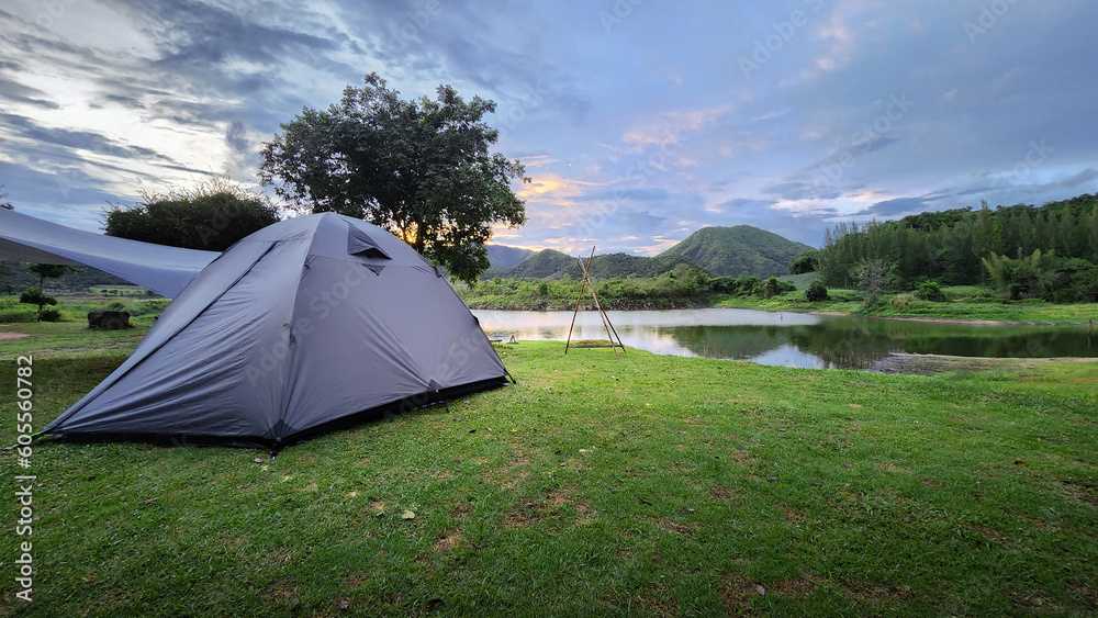 Classic hiking tent camping in the forest on the beach of mountain river, setting up a tent in the mountains, a gray awning from the rain. Classic hiking tent camping in the forest on the beach of mountain river, setting up a tent in the mountains, a gray awning from the rain.