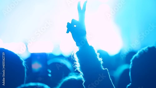 Girl making peace sign with her hand and waving it during live performance in front of stage photo