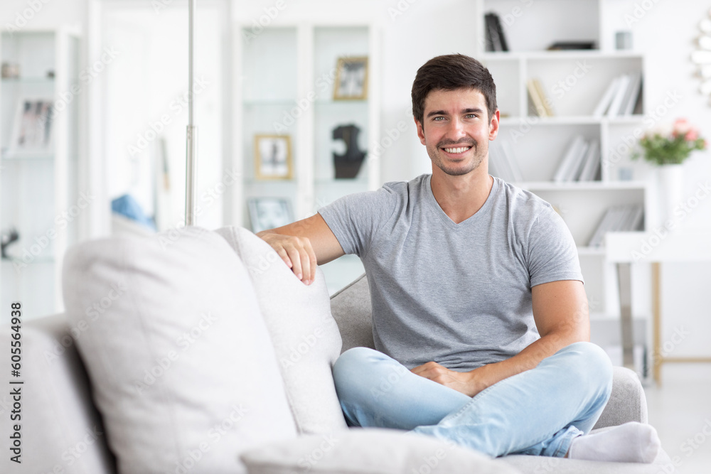 Portrait young happy man with a healthy smile sitting on sofa at home.
