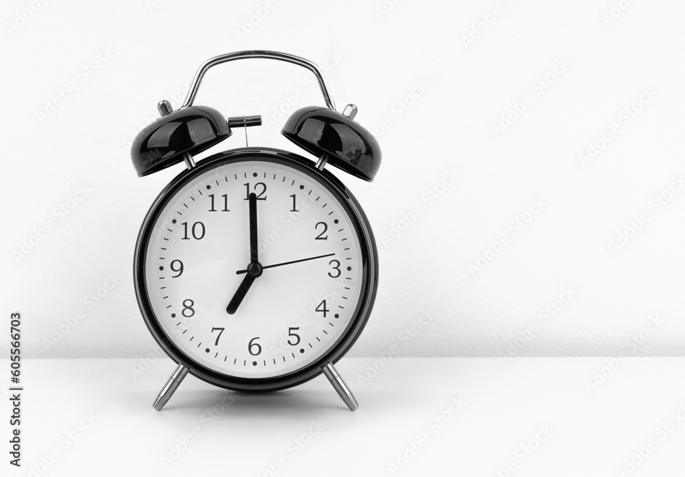 Black alarm clock on white wall background Black alarm clock on white wall background