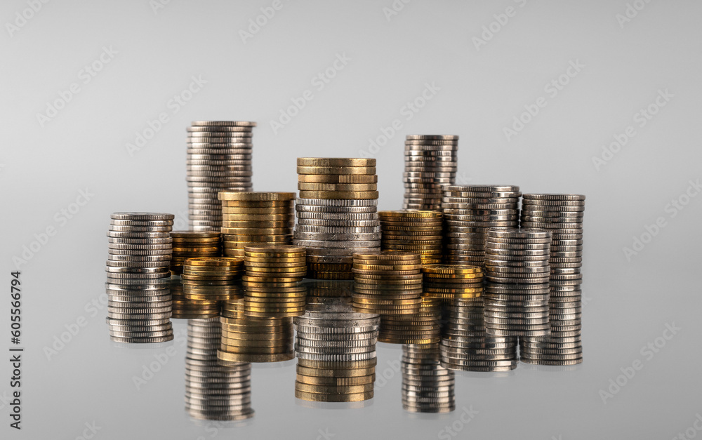 Stacks of coins in reflection on a grey background