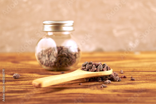 Black salt Kala namak in a glass salt shaker and on a wooden spoon on the table