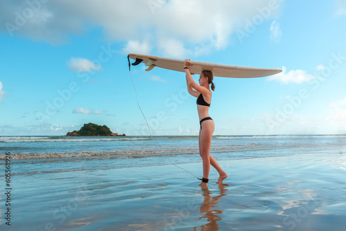 Surfing, Girl surfer with a longboard on the beach of Weligama, Indian Ocean Active water sports, travel, surf school, surf camps. Active lifestyle