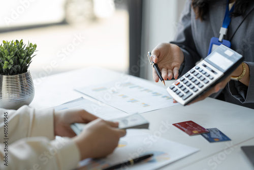 Young Asian businesswoman, company employee offering credit limit and interest rate calculation to customer for credit card Paying on the table at the office loan concept approval limit.