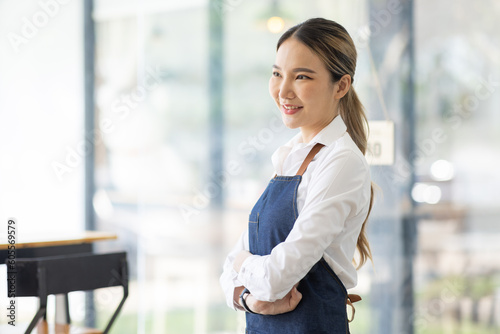 Asian Happy business woman is a waitress in an apron, the owner of the cafe stands at the door with a sign Open waiting for customers , cafes and restaurants Small business concept. 