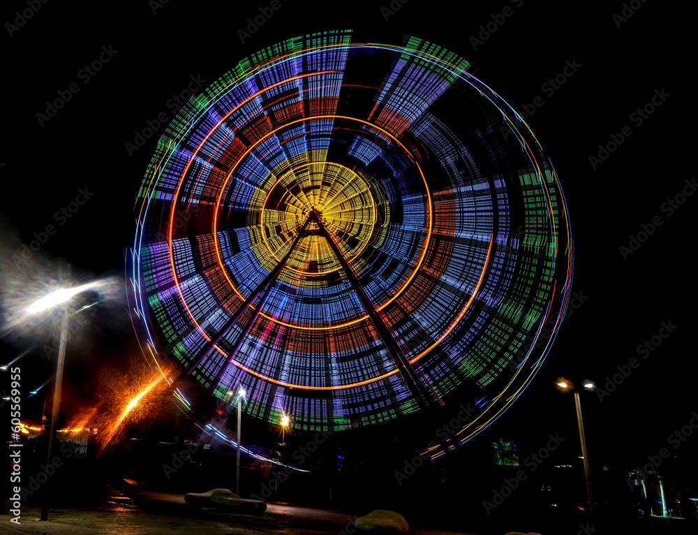 Obraz premium illumination of Ferris wheel in motion at the amusement park, night scene. bright colorful illumination. Long exposure shot. BATUMI, Adjara, GEORGIA. nightlife. isolated on black background.