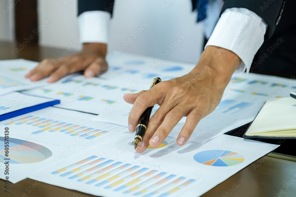 Businessman hand holding pen, analysis the graph with laptop at the home office for setting challenging business goals And planning to achieve the new target Businessman hand holding pen, analysis the graph with laptop at the home office for setting challenging business goals And planning to achieve the new target