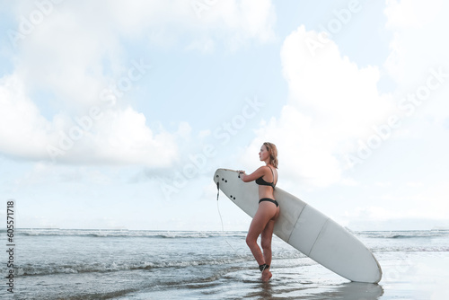 Surfing, Girl surfer with a longboard on the beach of Weligama, Indian Ocean Active water sports, travel, surf school, surf camps. Active lifestyle