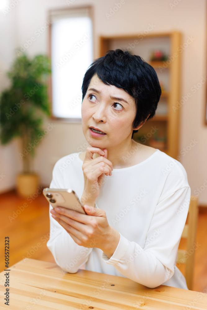 自宅で携帯電話を使用している成熟した日本人女性 自宅で携帯電話を使用している成熟した日本人女性