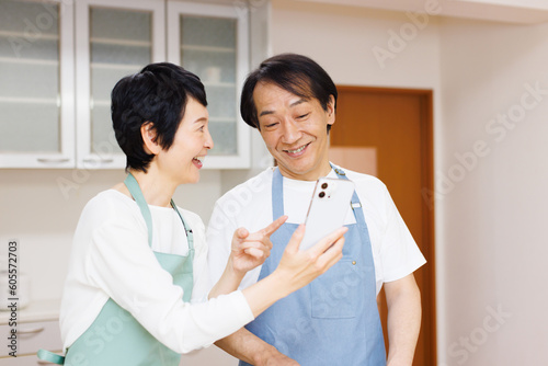 キッチンに携帯電話を持つ成熟した日本のカップル