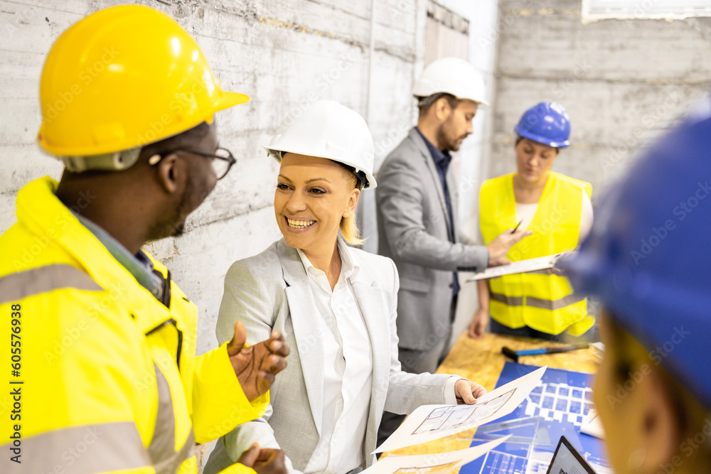 Team of experienced architects and engineers analyzing and looking at building plant at construction site. Team of experienced architects and engineers analyzing and looking at building plant at construction site.
