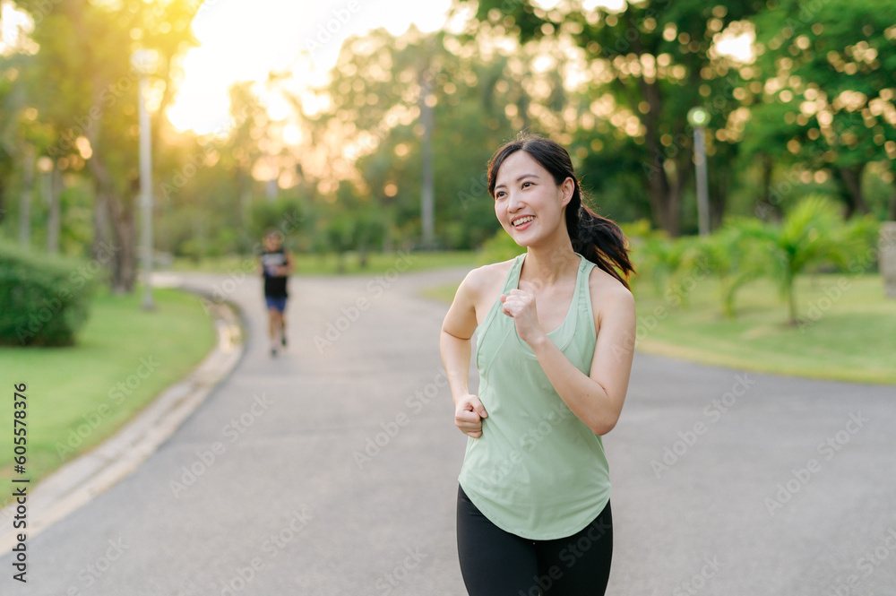 Fit Asian young woman jogging in park smiling happy running and enjoying a healthy outdoor lifestyle. Female jogger. Fitness runner girl in public park. healthy lifestyle and wellness being concept Fit Asian young woman jogging in park smiling happy running and enjoying a healthy outdoor lifestyle. Female jogger. Fitness runner girl in public park. healthy lifestyle and wellness being concept