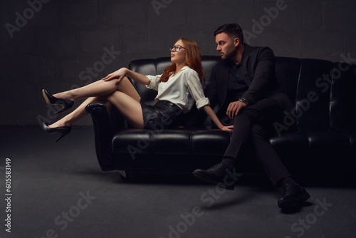 Stylish couple sitting on leather sofa together