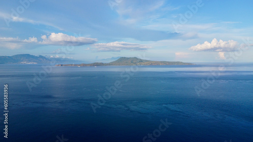 View of the Verde island. Philippines. Aerial view of a tropical island on the horizon, white clouds, calm sea.