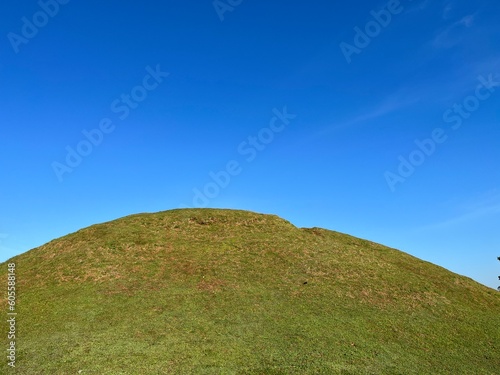 Landscape view of green meadow hill with clear blue sky on the background.