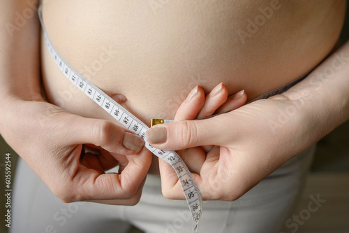 A fat woman measures her waist with a measuring tape, close-up.Lifestyle, diet concept.
