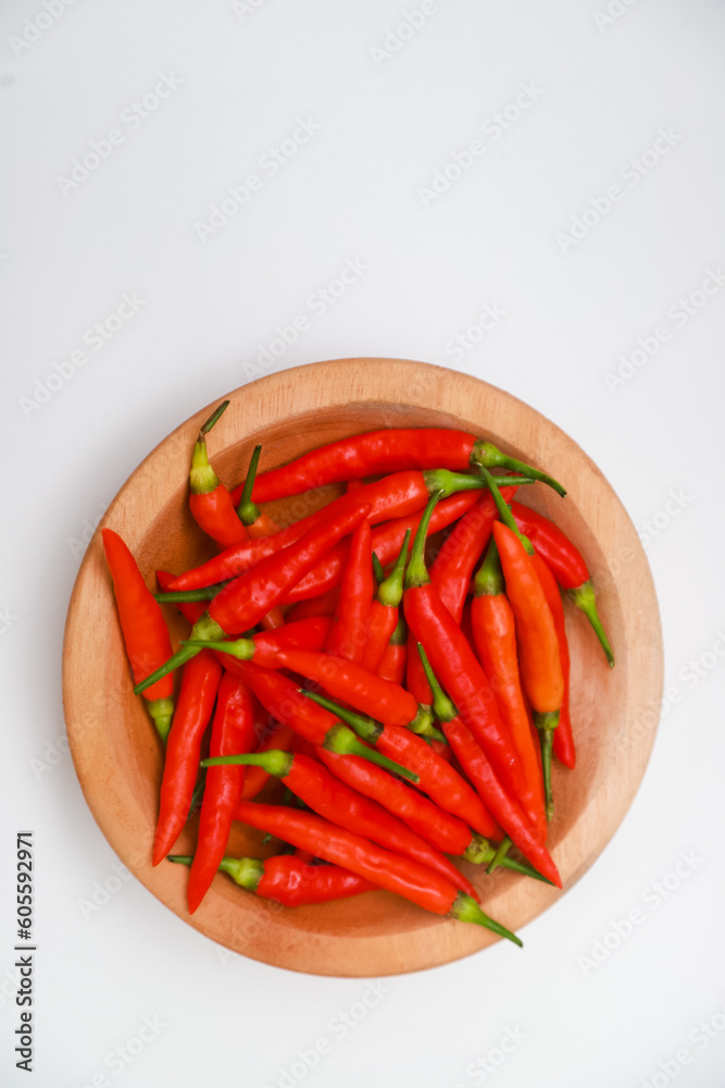 Top view of red chilies on a wooden plate on a white background Top view of red chilies on a wooden plate on a white background