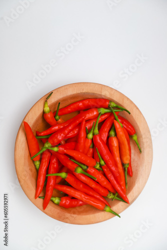 Top view of red chilies on a wooden plate on a white background