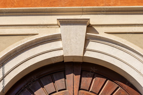 Closeup of an ancient marble arch with keystone and brown wooden door, full frame, photography. Brescia downtown, Lombardy, Italy, Europe.