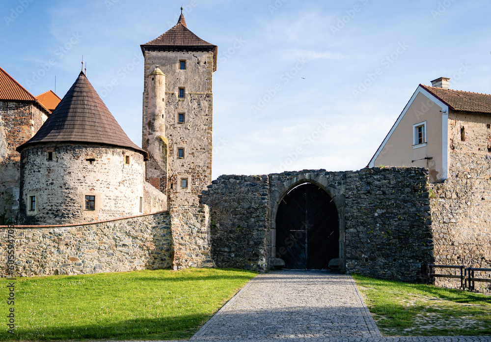 Gothic water castle Svihov (Švihov) with the bright yellow field and tree branches in the foreground. Pilsen region. Czech republic. Gothic water castle Svihov (Švihov) with the bright yellow field and tree branches in the foreground. Pilsen region. Czech republic.
