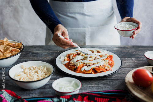 Mexican woman hands preparing chilaquiles with red sauce and eating traditional mexican food for breakfast in Mexico Latin America, hispanic people