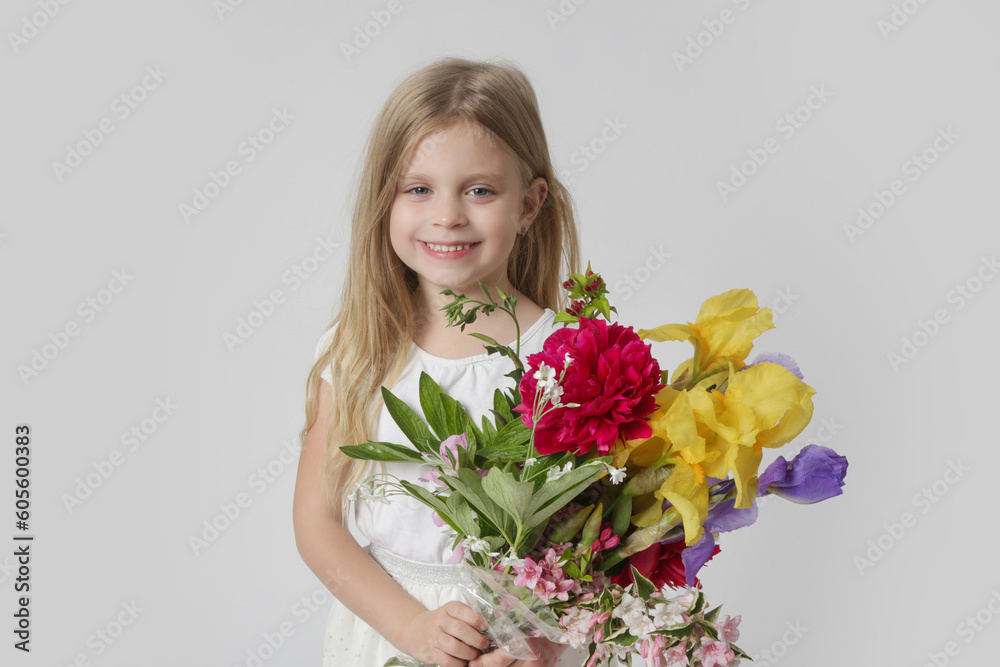 Studio portrait of beautiful little girl holding big colorful bouquet of various flowers.