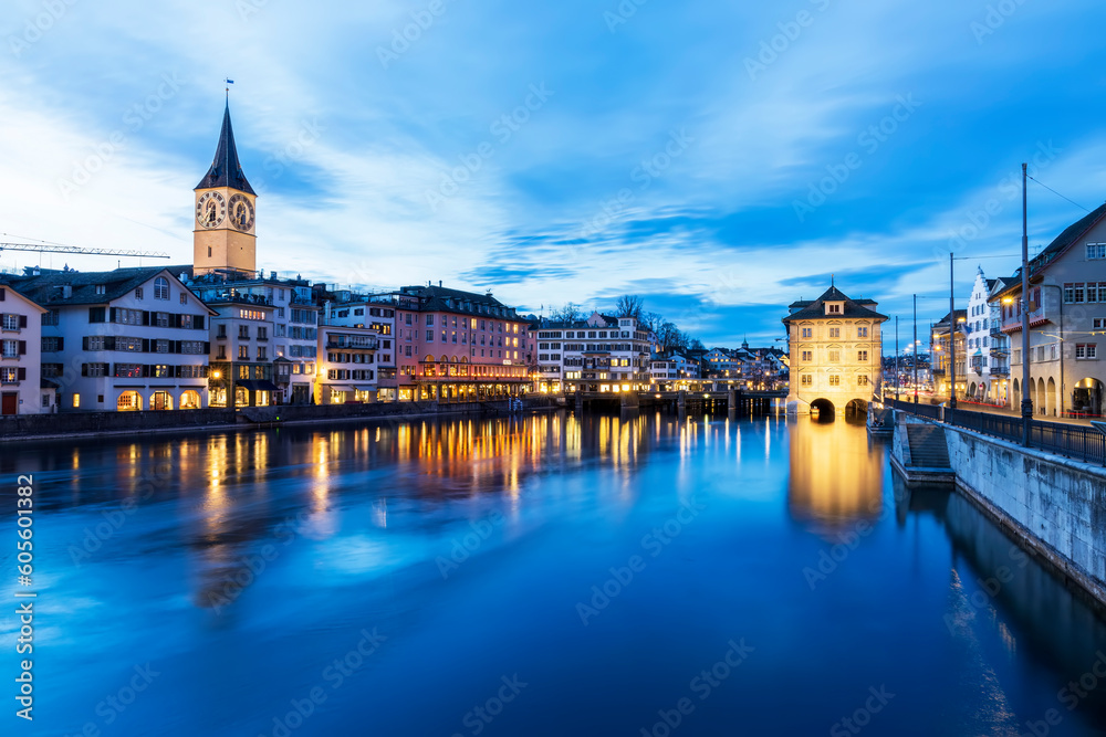Panorama landscape along Limmat river in twilight sunset with background.Blue sky in the evening.Winter season in Switzerland with reflection on Limmat river.Colorful light cityscape.Clock and bridge.