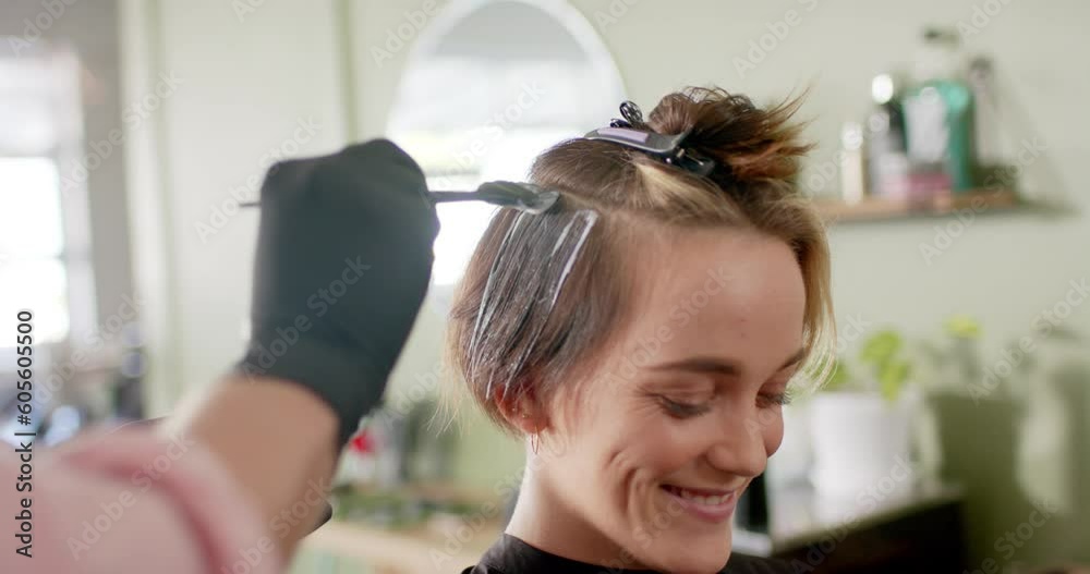 Hand of caucasian male hairdresser dyeing happy female client's hair at salon, in slow motion Hand of caucasian male hairdresser dyeing happy female client's hair at salon, in slow motion
