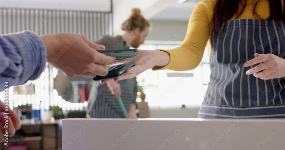 Midsection of caucasian female hairdresser and client paying with smartphone, in slow motion Midsection of caucasian female hairdresser and client paying with smartphone, in slow motion