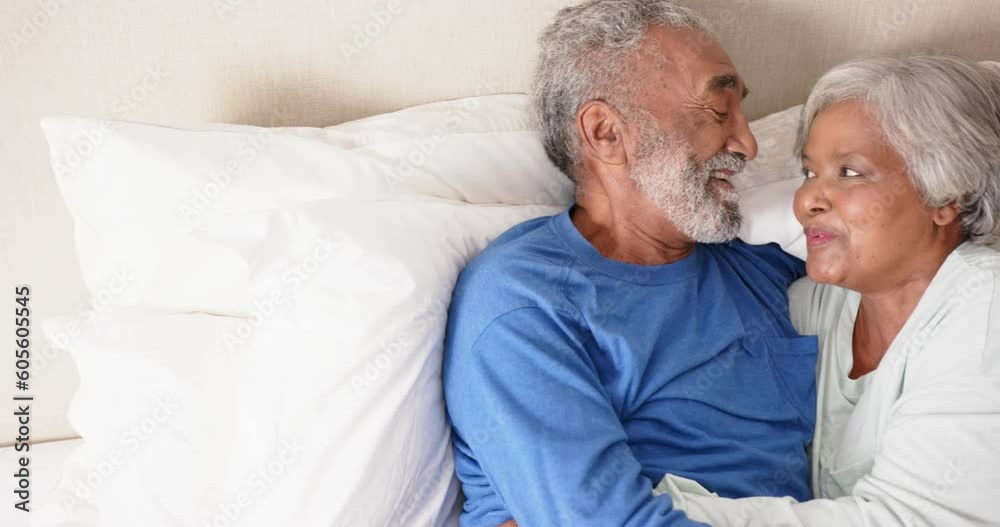 Happy senior biracial couple lying on bed and embracing, unaltered, in slow motion Happy senior biracial couple lying on bed and embracing, unaltered, in slow motion