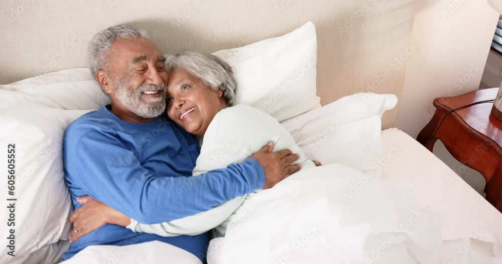 Happy senior biracial couple lying on bed and embracing, unaltered, in slow motion Happy senior biracial couple lying on bed and embracing, unaltered, in slow motion