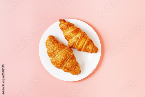 Plate with delicious croissants on a pink background. french pastries. copy space.