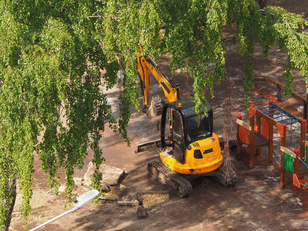 Mini excavator is carrying out work on the improvement of the urban area, medium plan, spring in the city. The work of municipal equipment in the city.