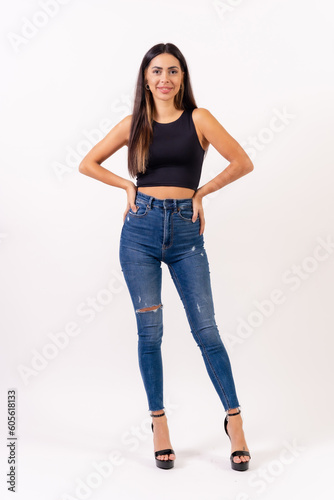 Brunette woman in casting photos on a white background, in jeans and a black t-shirt smiling