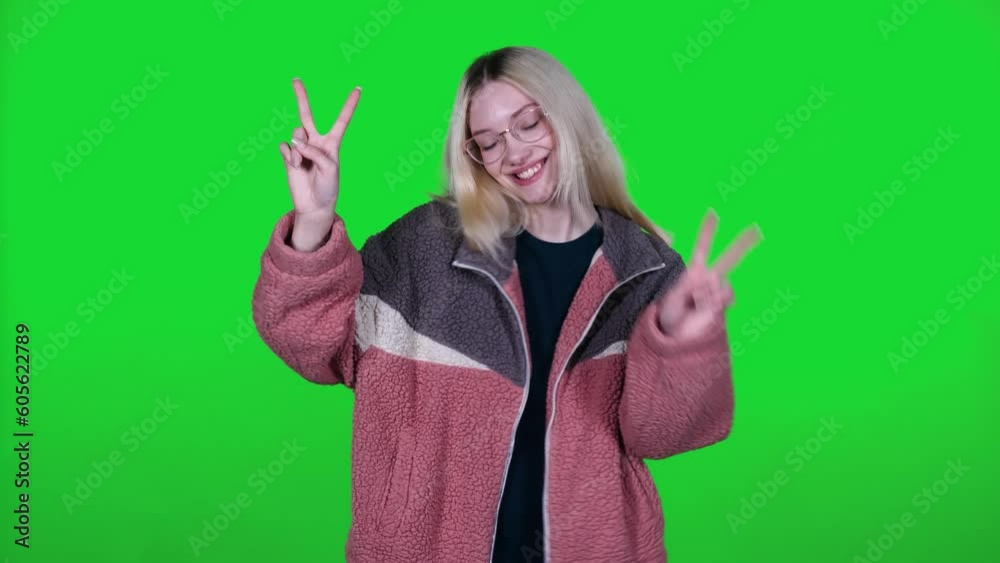 Pretty caucasian female dances and showing OK sign to the music on a green background, cheerful girl takes a video on for a social network, chroma key template Pretty caucasian female dances and showing OK sign to the music on a green background, cheerful girl takes a video on for a social network, chroma key template