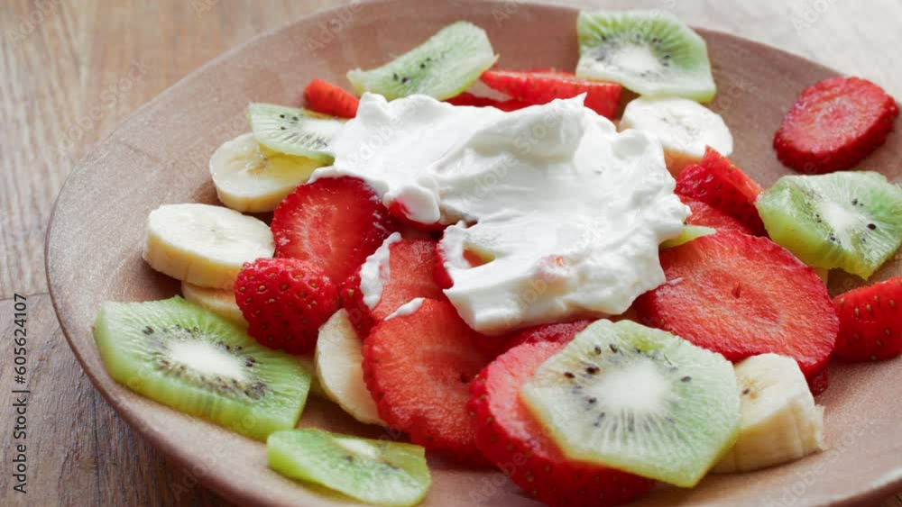 A fruit salad made from fresh fruits, including strawberries, bananas, and kiwis beautifully arranged in a bowl. Spread greek yogurt on top A fruit salad made from fresh fruits, including strawberries, bananas, and kiwis beautifully arranged in a bowl. Spread greek yogurt on top