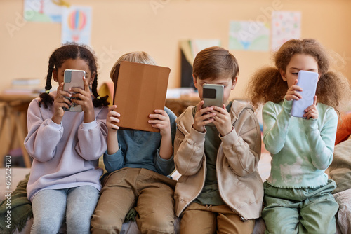 Group of young children holding smartphones and hiding faces, gen Alpha photo
