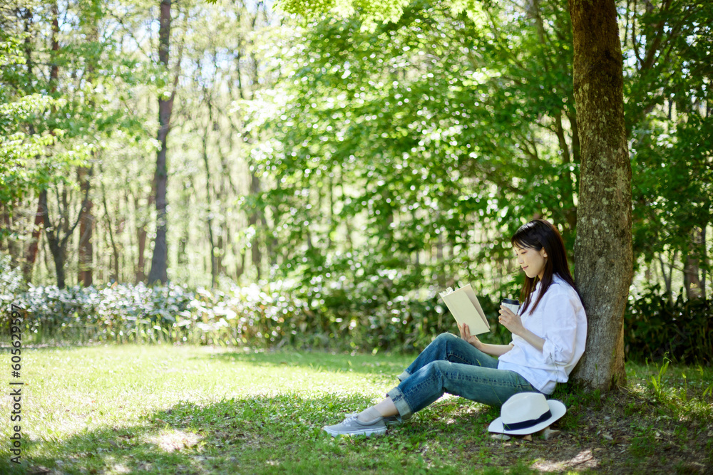 森の中でリラックスしながら読書をする30代日本人女性の初夏のイメージ 森の中でリラックスしながら読書をする30代日本人女性の初夏のイメージ