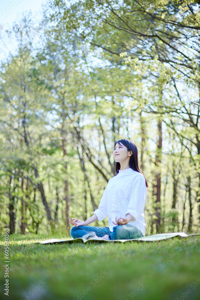 自然豊かな初夏の森でくつろぎながら瞑想を行う日本人女性 自然豊かな初夏の森でくつろぎながら瞑想を行う日本人女性