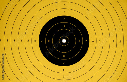close up of a yellow and black target perfectly hit in the center by a bulletin a shooting gallery