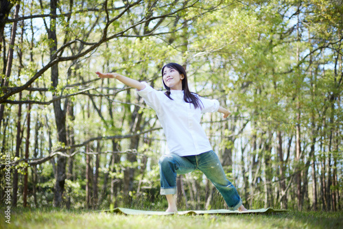 自然豊かな初夏の森でくつろぎながらヨガを楽しむ日本人女性