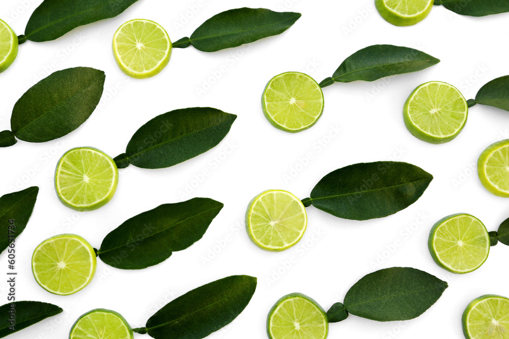 Fresh lime slices and green leaves on white background, flat lay