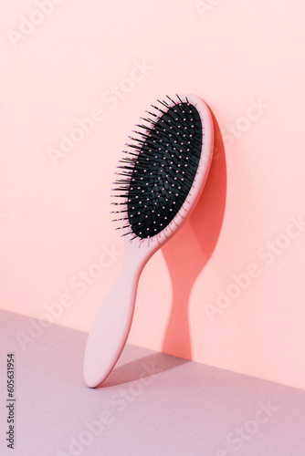 Paddle hair brush on pink and grey background with harsh shadow, closeup