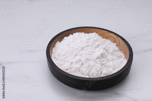 Wooden bowl of natural starch on white marble table, space for text