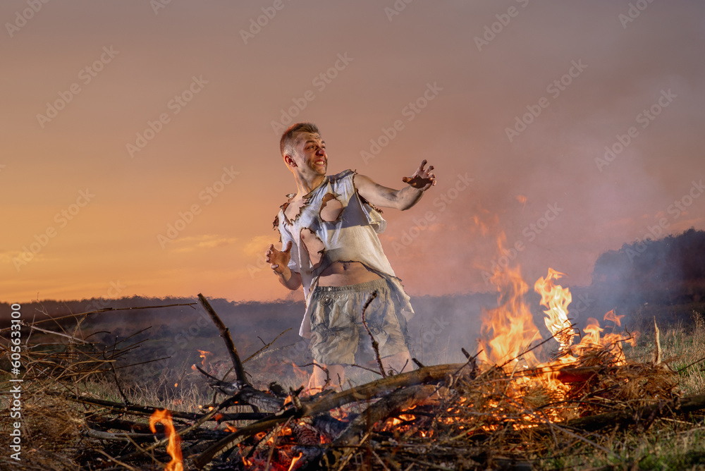 a civilian man in despair near burnt property, in burnt clothes, around a field, war