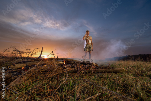 a civilian man in despair near burnt property, in burnt clothes, around a field, war