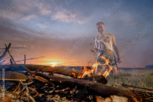 a civilian man in despair near burnt property, in burnt clothes, around a field, war