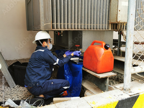 Electrician taking samples of transformer oil to test the dielectric strength after the annual repair work.